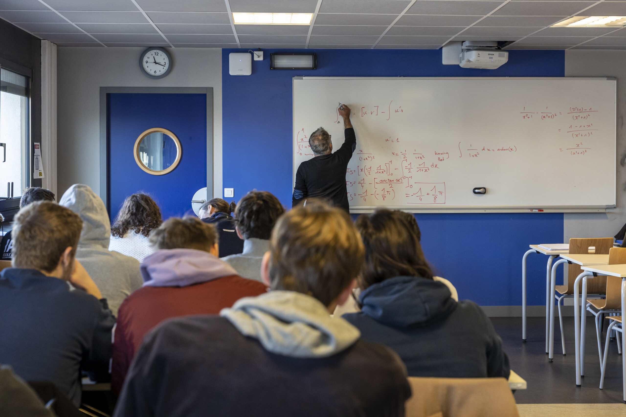 un professeur de l'école aéronautique et spatial écrit au tableau devant une classe