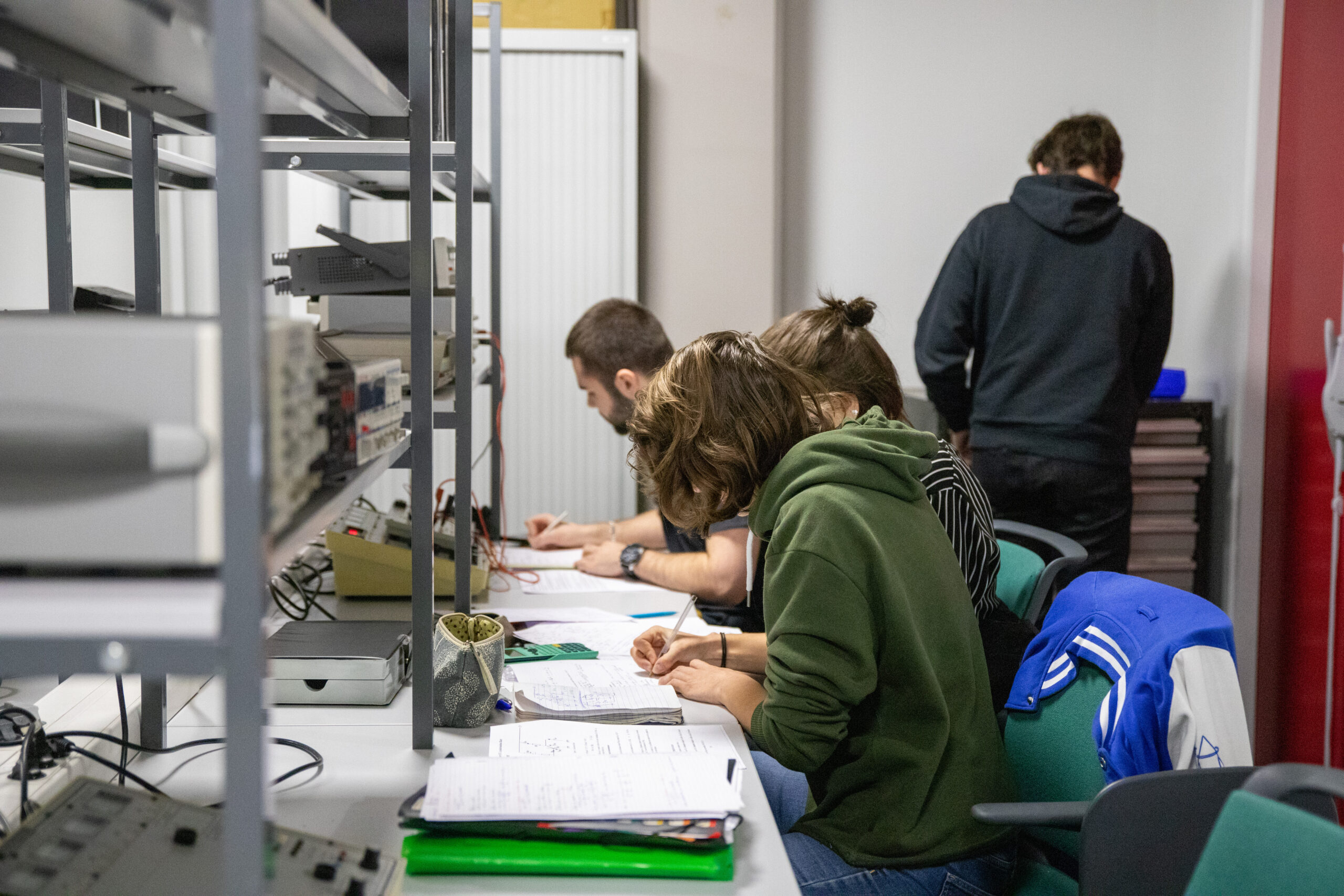 Des étudiants travaillent dans une salle avec des étagères recouvertes de manuels et de machines