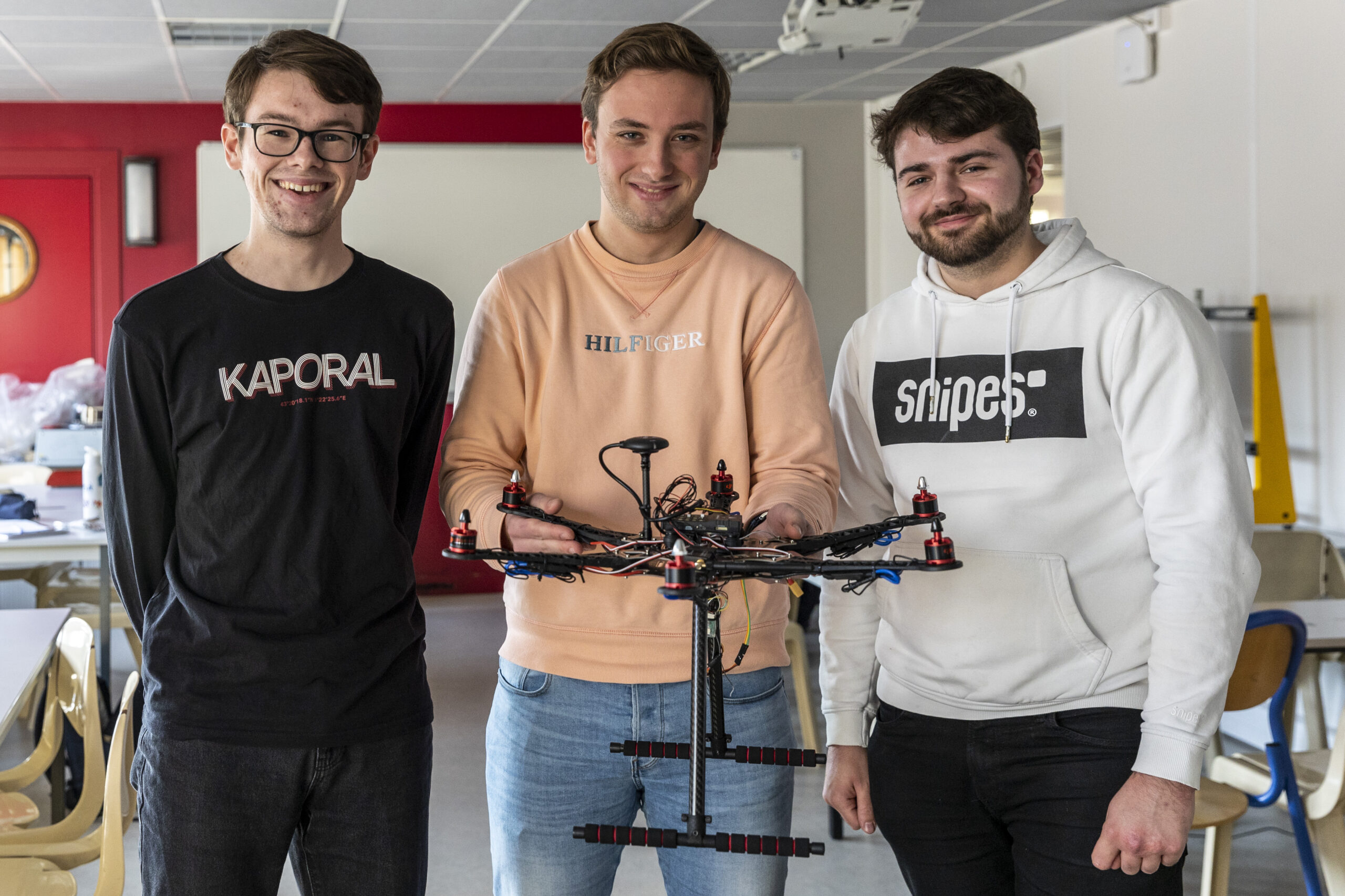 Trois étudiants posant fièrement avec l'une de leurs créations aéronautique et spatiale