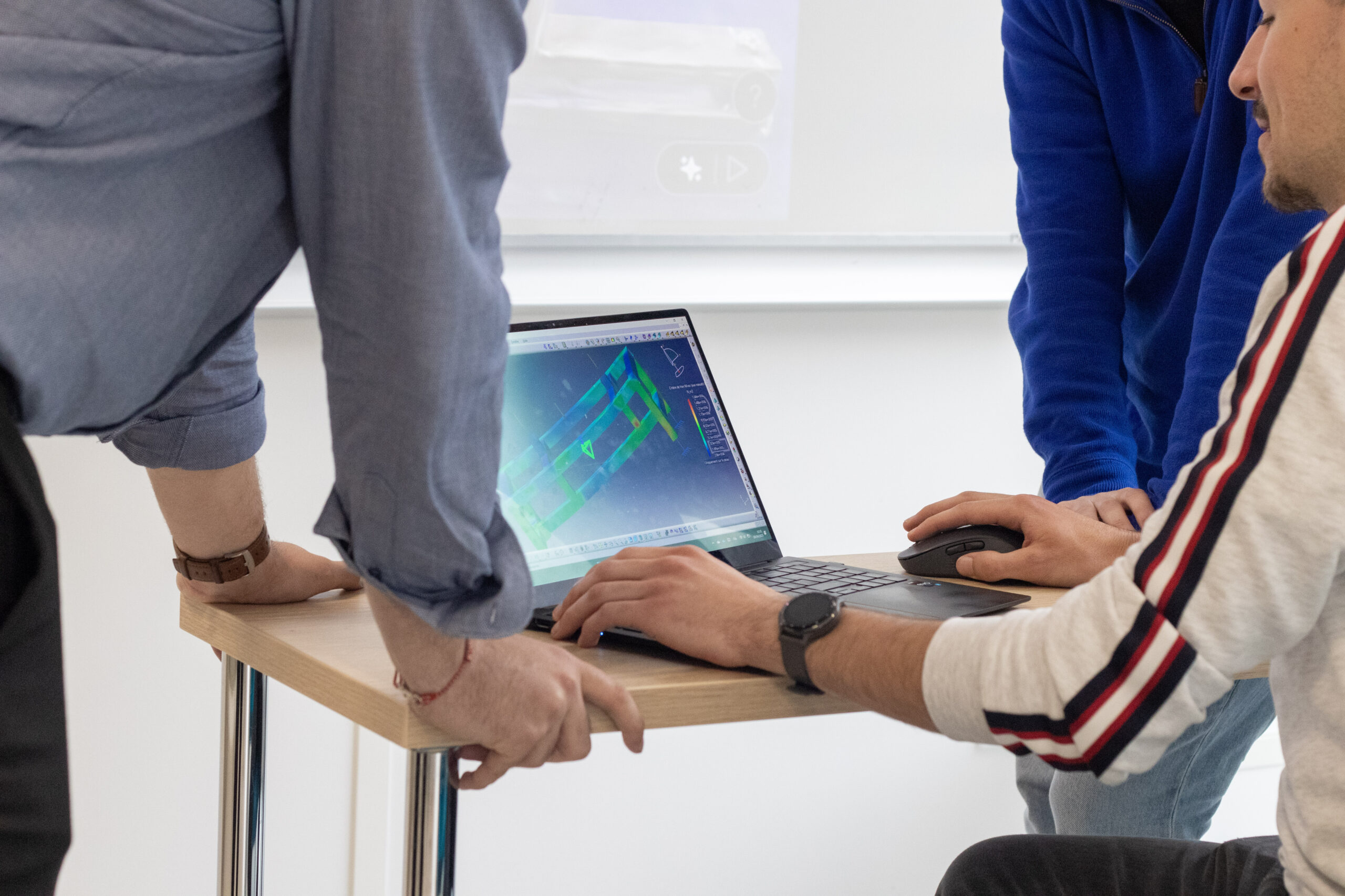 Trois hommes autour d'un ordinateur en train de regarder un graphique aéronautique ou spatial