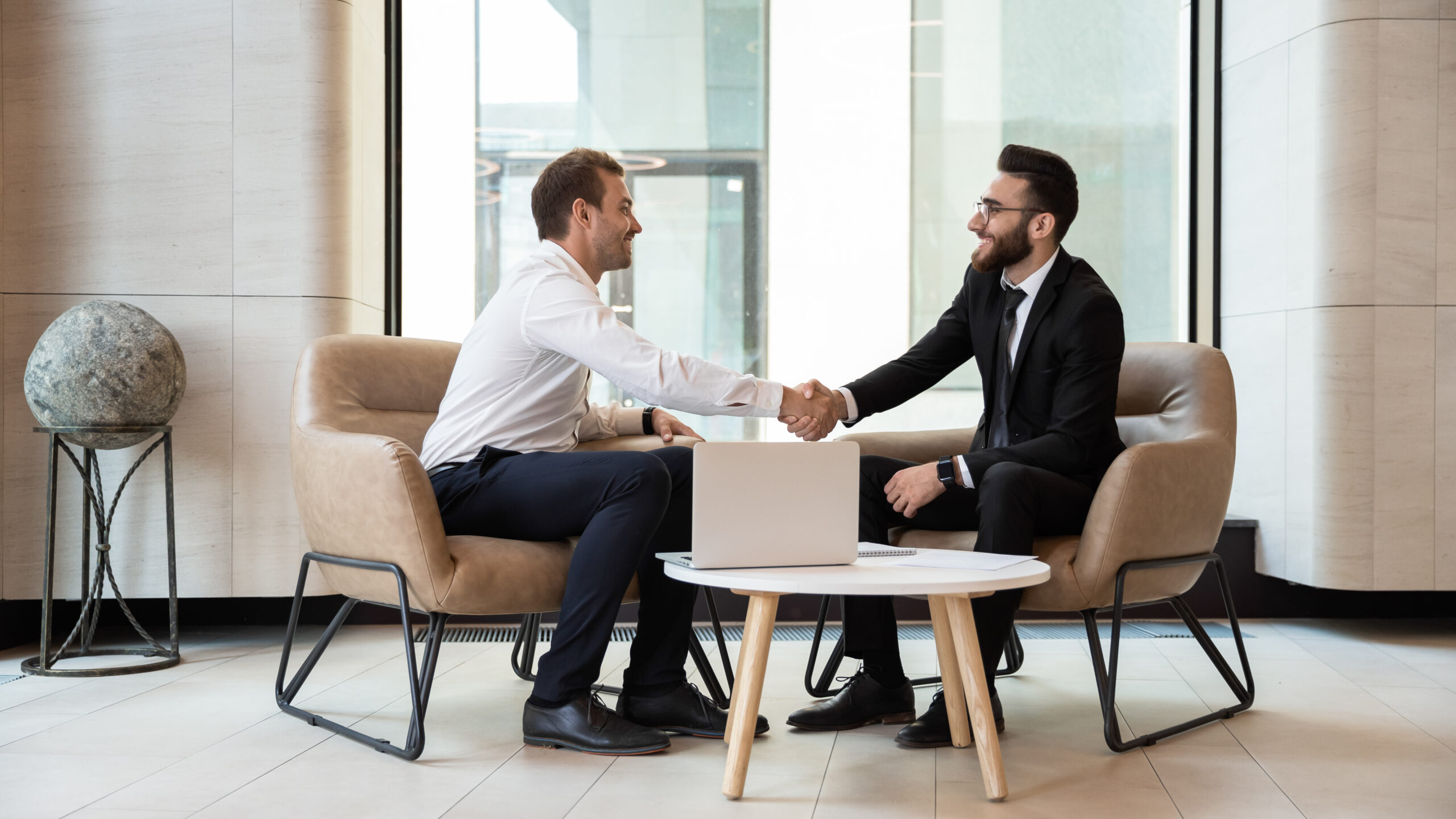 2 hommes se serrent la main autour d'une table