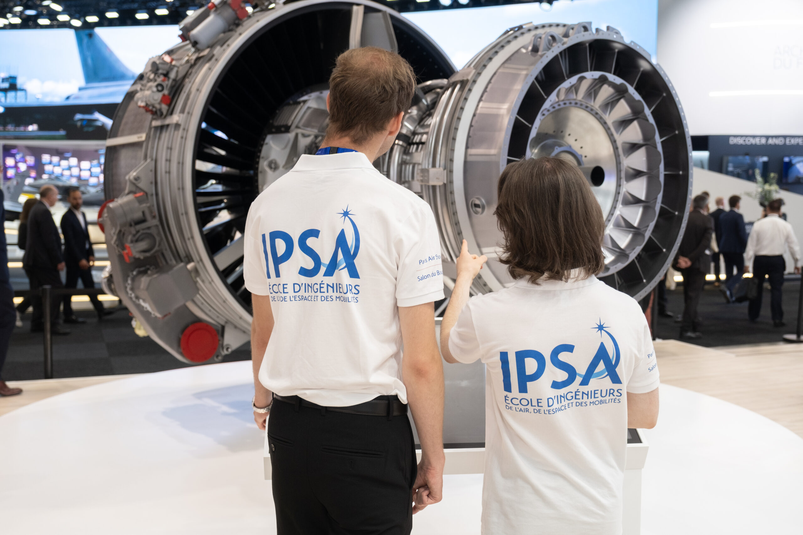 Deux étudiants de l'IPSA, de dos, pointant du doigt un moteur d'avion au salon du Bourget 2025